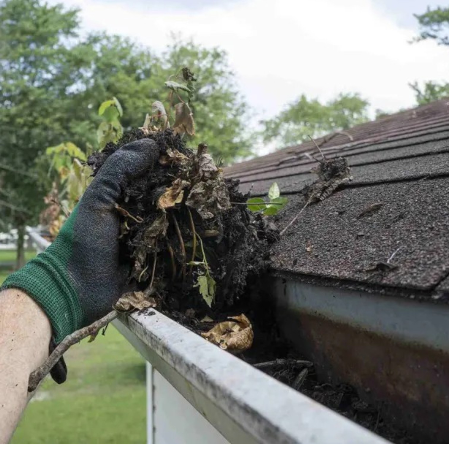 Hand removing debris during gutter cleaning on a residential roof